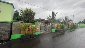 A gated residential area with a concrete wall, green accents, and a metal gate. - Gorgeous 3-bedroom villa in cool Wonosobo for relaxing stays (Wonosobo)