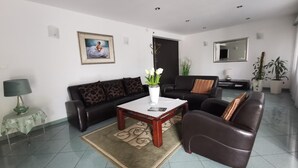 A living room with a sofa set, a coffee table, a lamp, a framed picture on the wall, and a potted plant. - Hotel Zieliniec (Poznań)