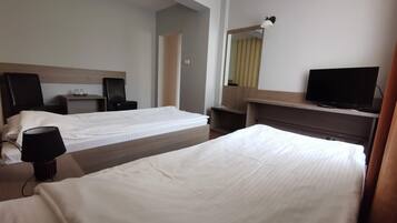 A hotel room with two beds, a television, a desk, and a mirror.