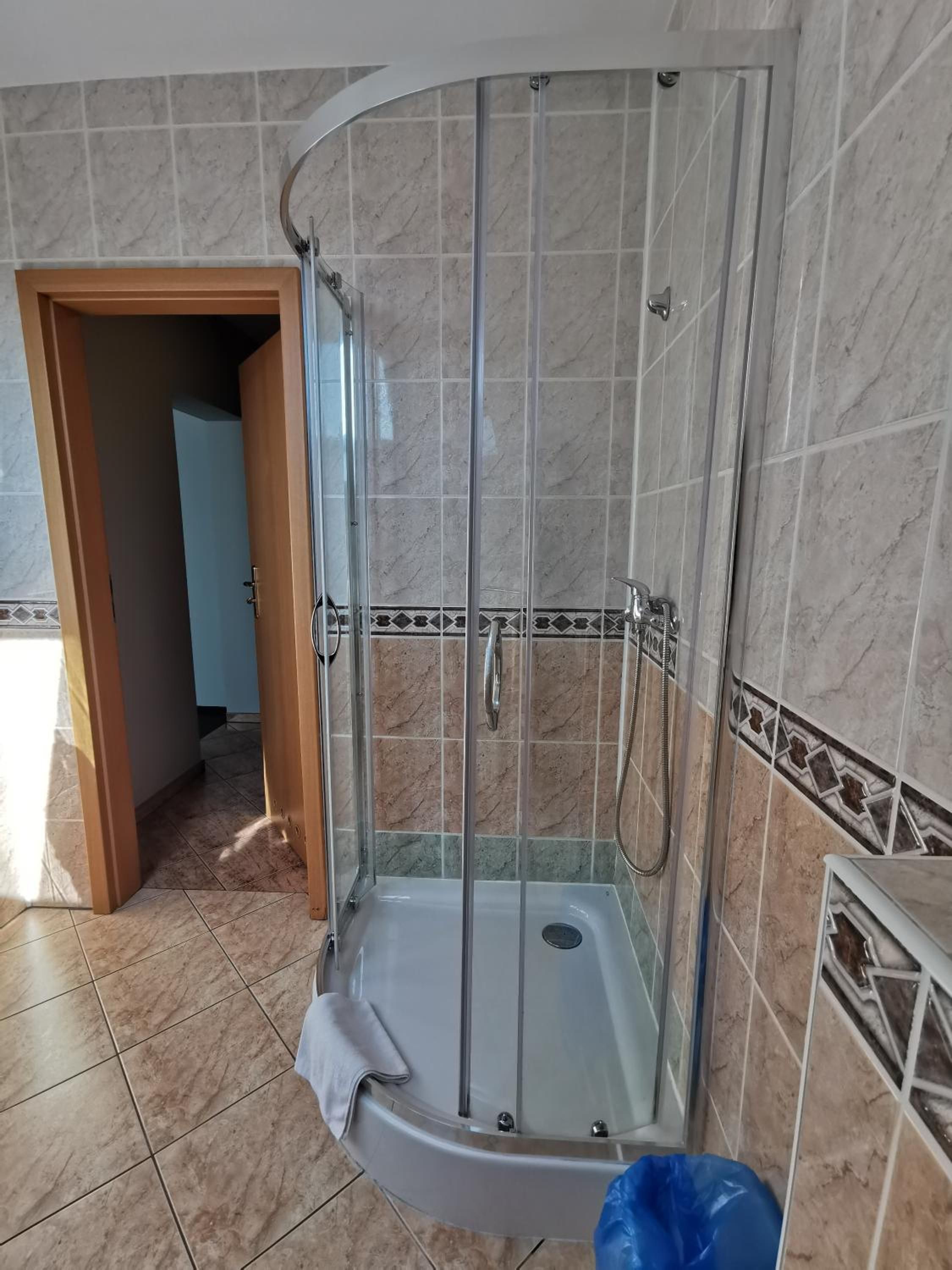 A bathroom with a shower enclosure, tiled walls, and a visible door leading to another room.
