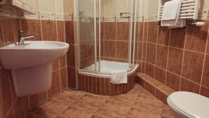 A bathroom with a glass-enclosed shower, a sink, and a toilet. - Hotel Zieliniec (Poznań)