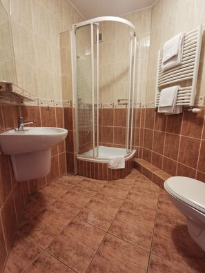 Un baño con ducha de vidrio, lavamanos e inodoro.