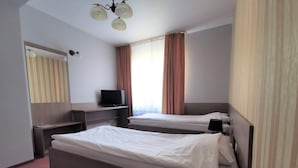 Ein Hotelzimmer mit zwei Betten, einem Fernseher, einem Schreibtisch und einem Spiegel.