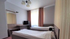 A hotel room with two beds, a television, a desk, and a mirror. - Hotel Zieliniec (Poznań)