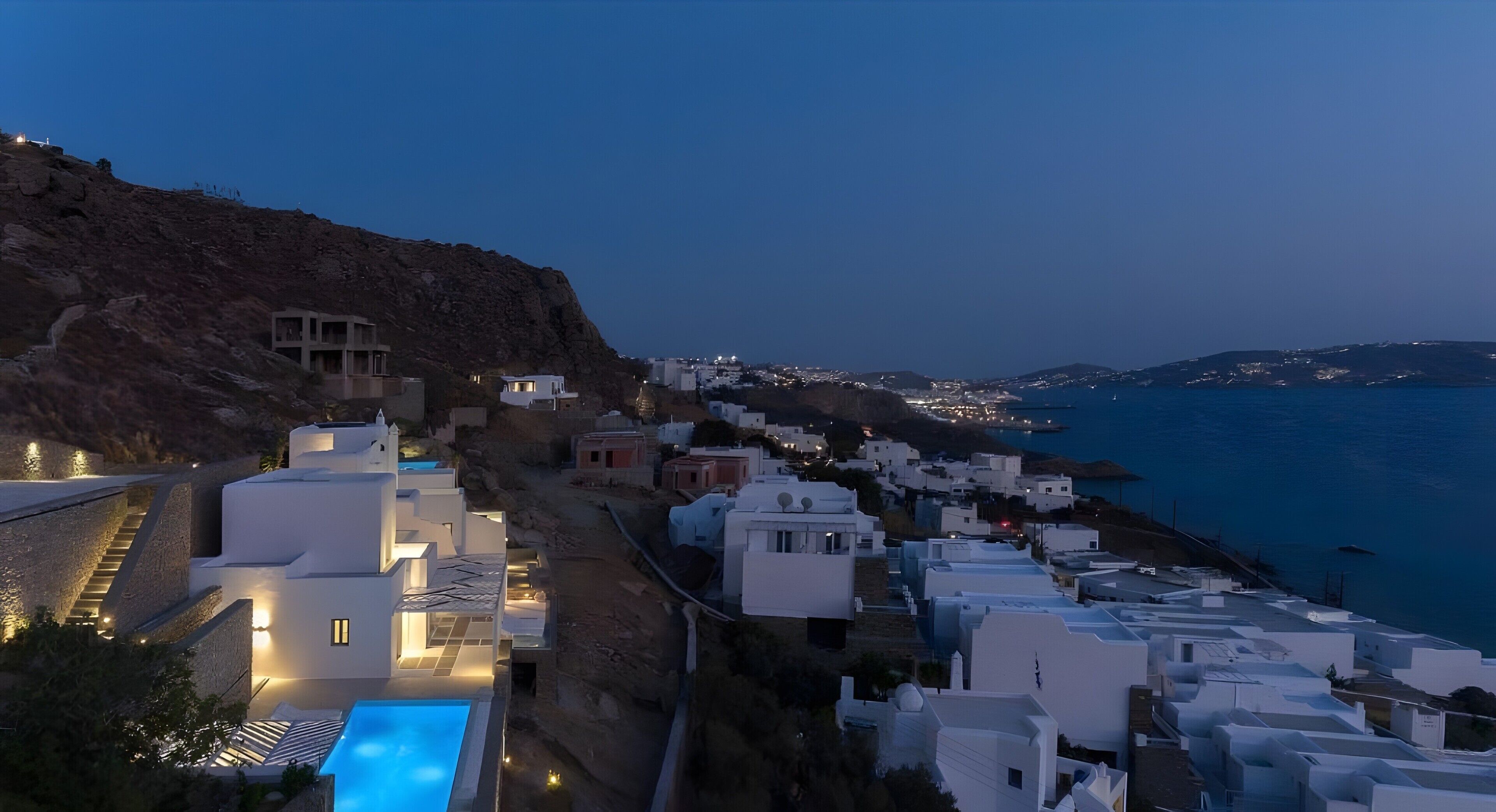 Un village côtier aux bâtiments blancs, doté d’une piscine et offrant une vue sur la mer.
