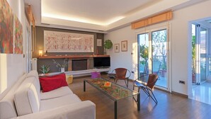 Uma sala de estar moderna com sofá, mesa de centro, cadeiras, lareira e televisão.