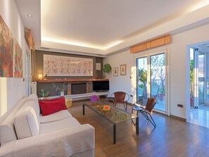 A modern living room with a sofa, coffee table, and chairs, a fireplace, and a television. - AthensView Bird’s Eye Penthouse with Acropolis view (Athina)
