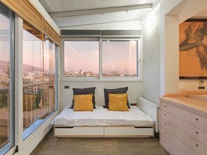 A bedroom with a bed, two pillows, a dresser, and a large window with a city view. - AthensView Bird’s Eye Penthouse with Acropolis view (Athina)