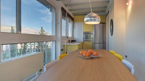 Cozinha moderna com mesa de jantar, tigela de frutas e luminária pendente.