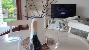 Una mesa de comedor con una botella de vino, dos copas de vino y una rama decorativa.
