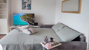 Un dormitorio moderno con un televisor grande, una cama con una bandeja de té y un cuadro en la pared.