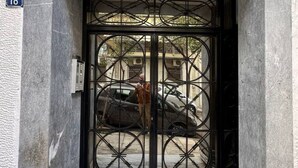 A building entrance with a large metal gate, a number '18' sign, and a vehicle parked outside. - AthensView Skyline: 5th fl, 2BR, Acropolis View (Athina)