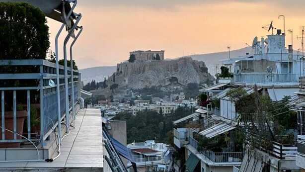 A view of a cityscape with a prominent ancient structure on a hill, modern buildings, and a balcony with railings. - AthensView Skyline: 5th fl, 2BR, Acropolis View (Athina)
