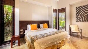 A bedroom with a bed, a chair, and a large window with a view of greenery. - O'hare Villa  (Jimbaran)