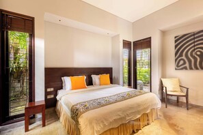 A bedroom with a bed, a chair, and a large window with a view of greenery. - O'hare Villa  (Jimbaran)