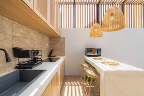 Eine moderne Küche mit Steinrückwand, schwarzen Geräten und einer Bar mit Hockern.