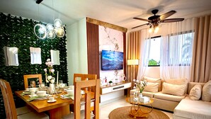 Ein modernes Wohnzimmer mit Essbereich, einer Sofagarnitur, einem Fernseher und einem Deckenventilator.