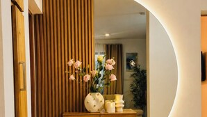 Ein modernes Interieur mit einer Holzwand, einem runden Spiegel und einer Konsolentisch mit Dekoration.