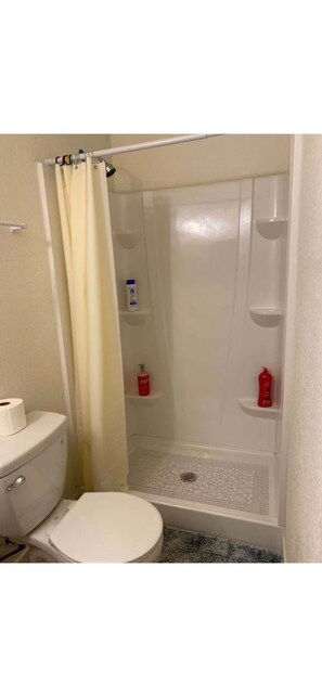 Ein Badezimmer mit Toilette, Dusche und Ablagen für Pflegeprodukte.