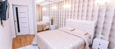 Ein Schlafzimmer mit einem großen Bett, einem Kleiderschrank, einem Spiegel und einer Chandelier.