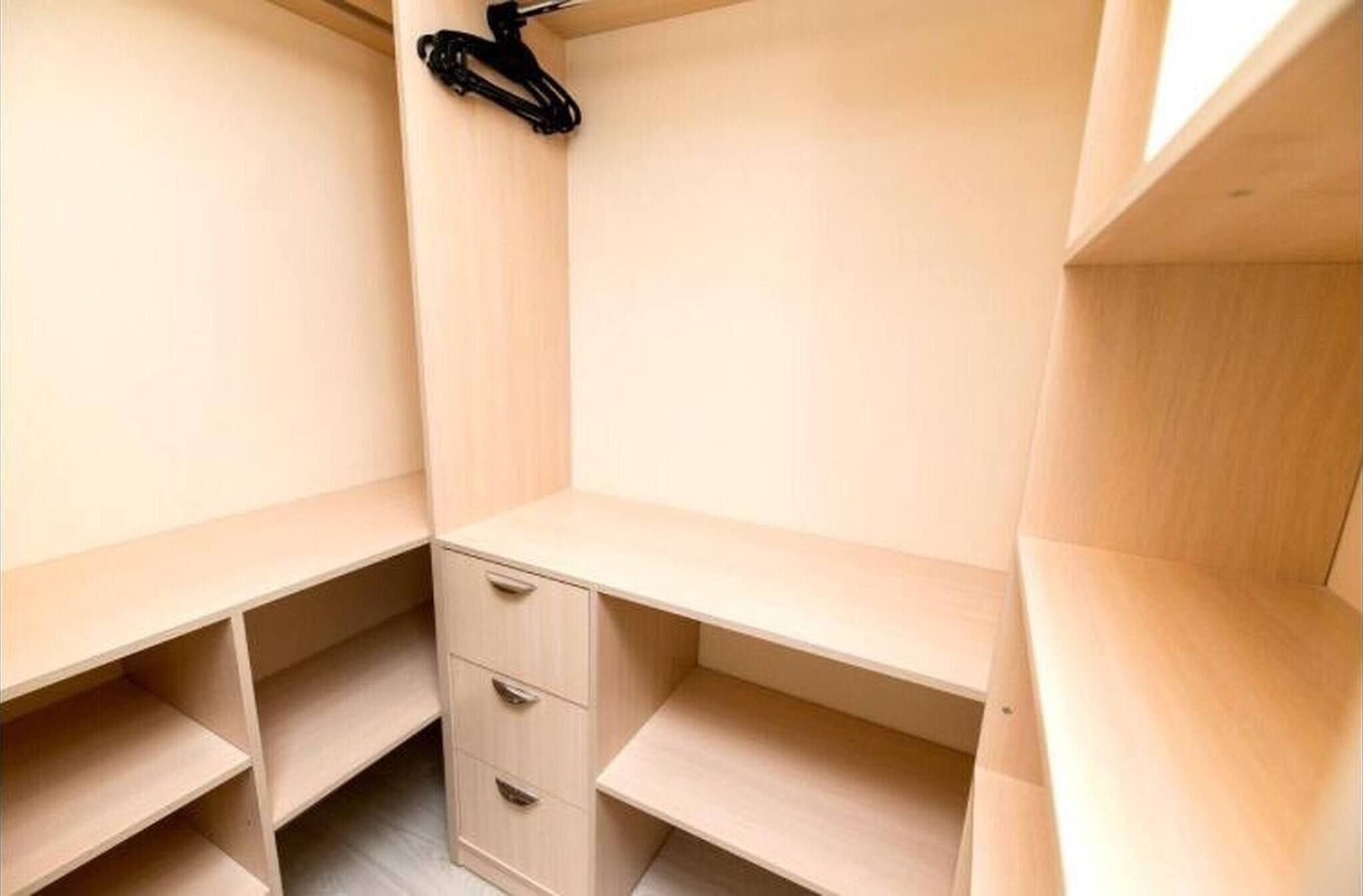 Ein Holzschrank mit offenen Regalen und einer Kleiderstange.