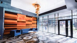 Un vestíbul modern amb un sofà blau, una taula de cafè rodona i un sòl de marbre únic.