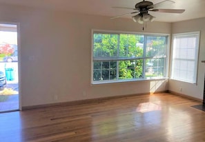 A room with hardwood flooring, a ceiling fan, and a large window with blinds. - Charming 2-bedroom house in beautiful San Mateo perfect for relaxing (San Mateo)