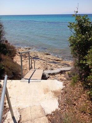 A beach with a wooden walkway leading to the water, surrounded by vegetation. - Sea View & Luxury Apartment Domania' with Wi-Fi and Air Conditioning (Καληκρατειας Σωζόπολη)