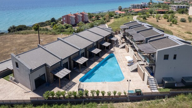 Een modern resort met een zwembad, meerdere gastenkamers en uitzicht op zee.