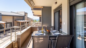 Een balkon met een eettafel, tuinmeubilair en uitzicht op de omliggende gebouwen.