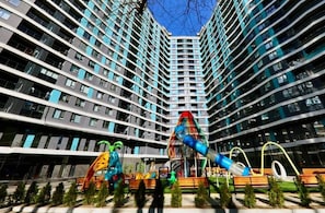 Un immeuble d’appartements moderne avec un terrain de jeux situé devant.
