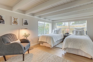 Ein Schlafzimmer mit zwei Betten, einem Sessel und Bildern an der Wand.