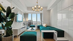 A modern living room with a sofa set, a TV, a coffee table, and a large plant. - Narel by Kozystay - Kuningan (Jakarta)