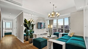 A modern living room with a large TV, seating area, and a city view. - Narel by Kozystay - Kuningan (Jakarta)