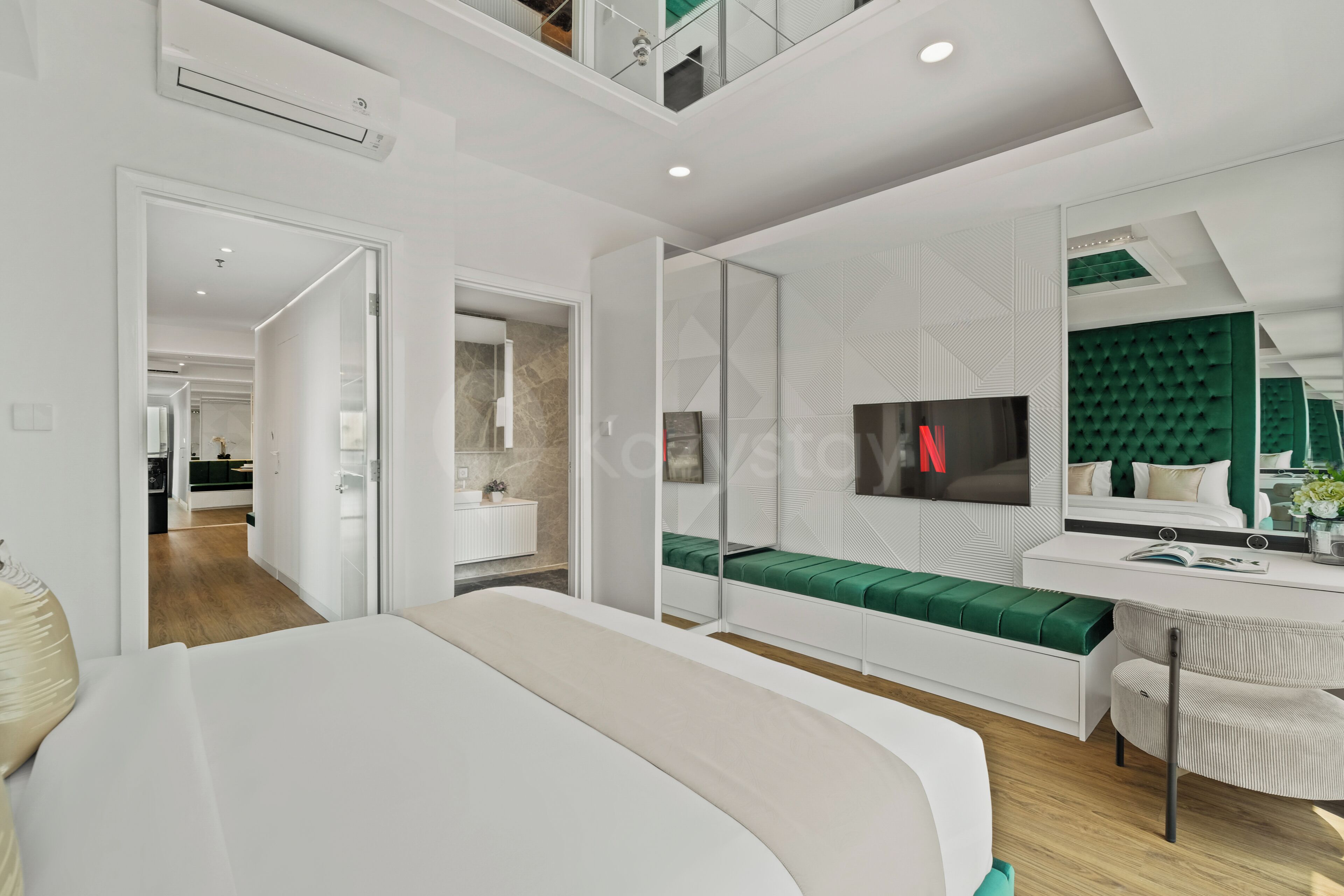 Una camera da letto moderna con un letto, una scrivania, un divano verde e una TV, con una parete verde a contrasto.