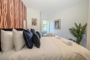 Ein Hotelzimmer mit Bett, Kissen, einer Pflanze und Kunstwerken an den Wänden.