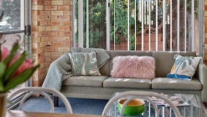 A cozy living area with a grey sofa, a pink fluffy pillow, and a green bowl on a glass table. - The Palms Sand Dune Middleton (Middleton)