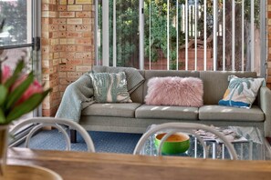 A cozy living area with a grey sofa, a pink fluffy pillow, and a green bowl on a glass table. - The Palms Sand Dune Middleton (Middleton)
