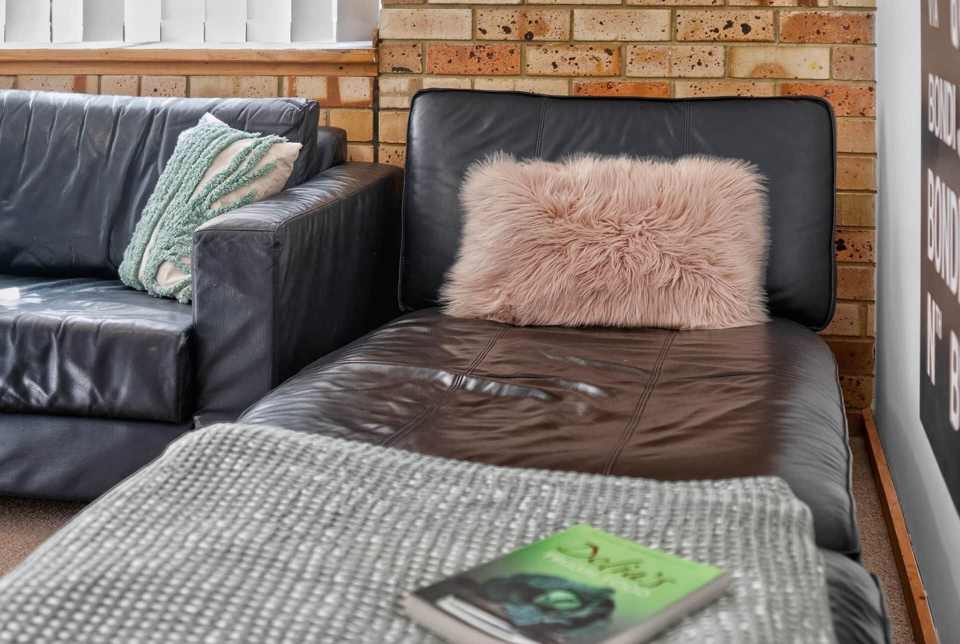 A modern living room with a leather sofa, a small couch, and a patterned rug.