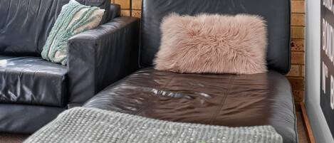 A modern living room with a leather sofa, a small couch, and a patterned rug.