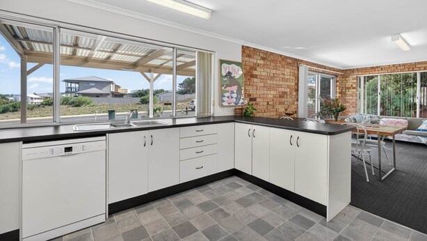 A modern kitchen with white cabinets, a large window, and a brick accent wall. - The Palms Sand Dune Middleton (Middleton)