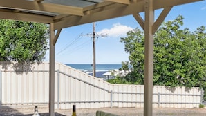 A covered outdoor seating area with a view of the ocean and a white fence. - The Palms Sand Dune Middleton (Middleton)