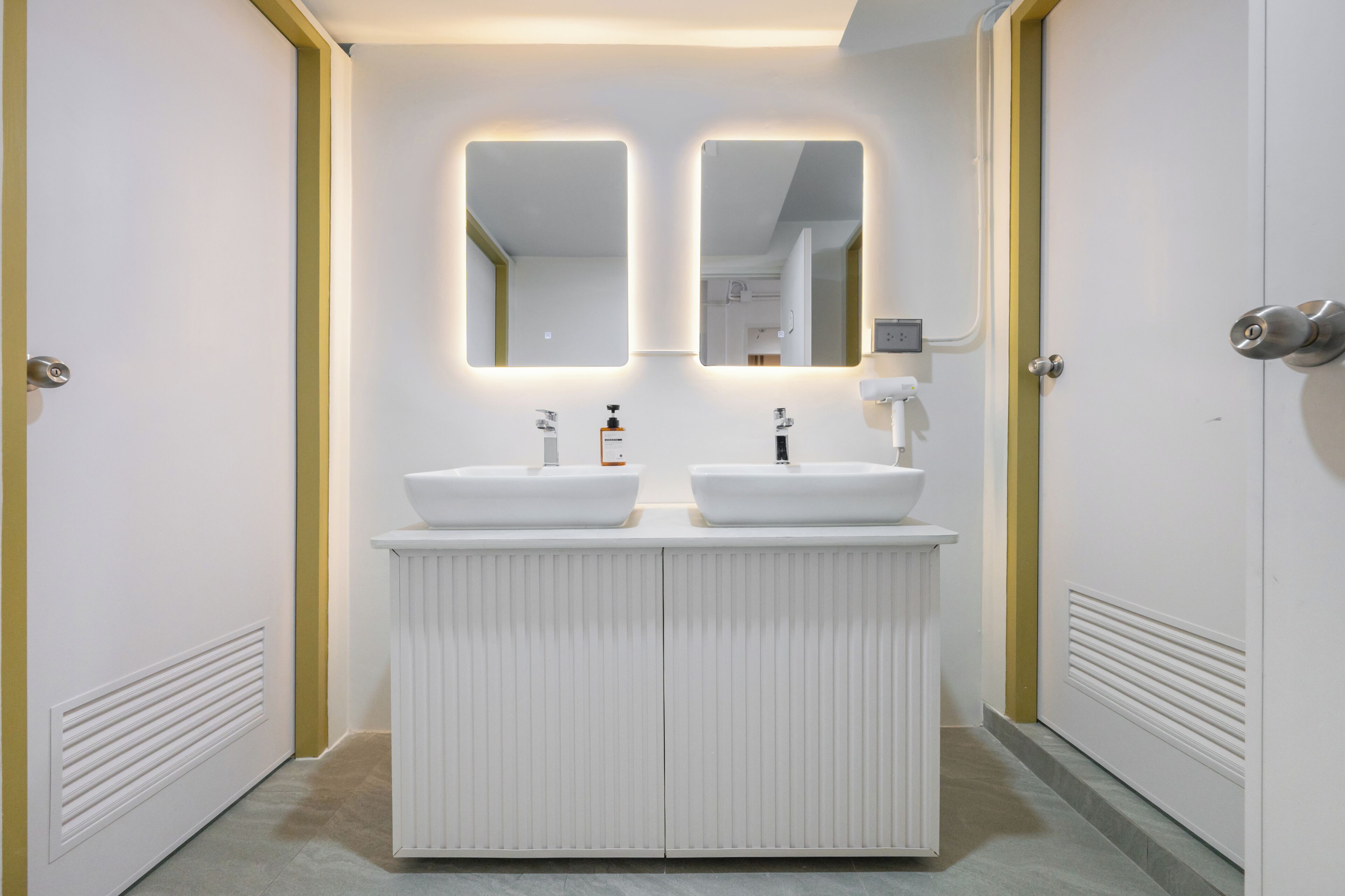 A modern bathroom with two sinks, a mirror, and a lighted wall.