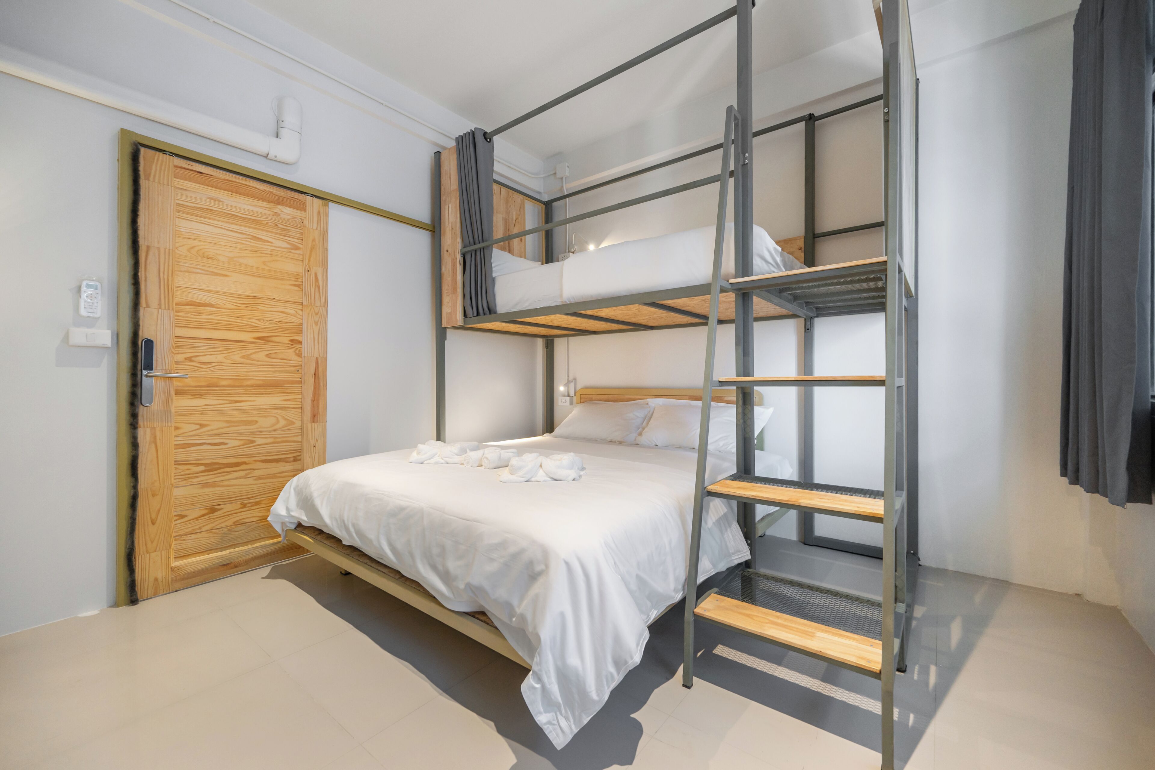 A bunk bed room with a wooden door and a white wall.