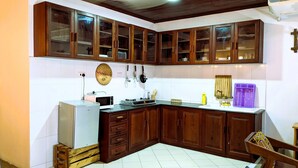A kitchen with wooden cabinets, a microwave, a stove, and a sink. - The Hub Train House Amazing Gents code (Zanzibar)