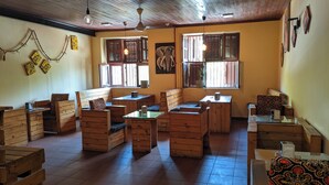 A rustic interior with wooden furniture, a large elephant painting, and a ceiling fan. - The Hub Train House Amazing Gents code (Zanzibar)