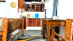 A kitchen with wooden cabinets, a woven bench, and a patterned rug. - The Hub Train House Amazing Gents code (Zanzibar)