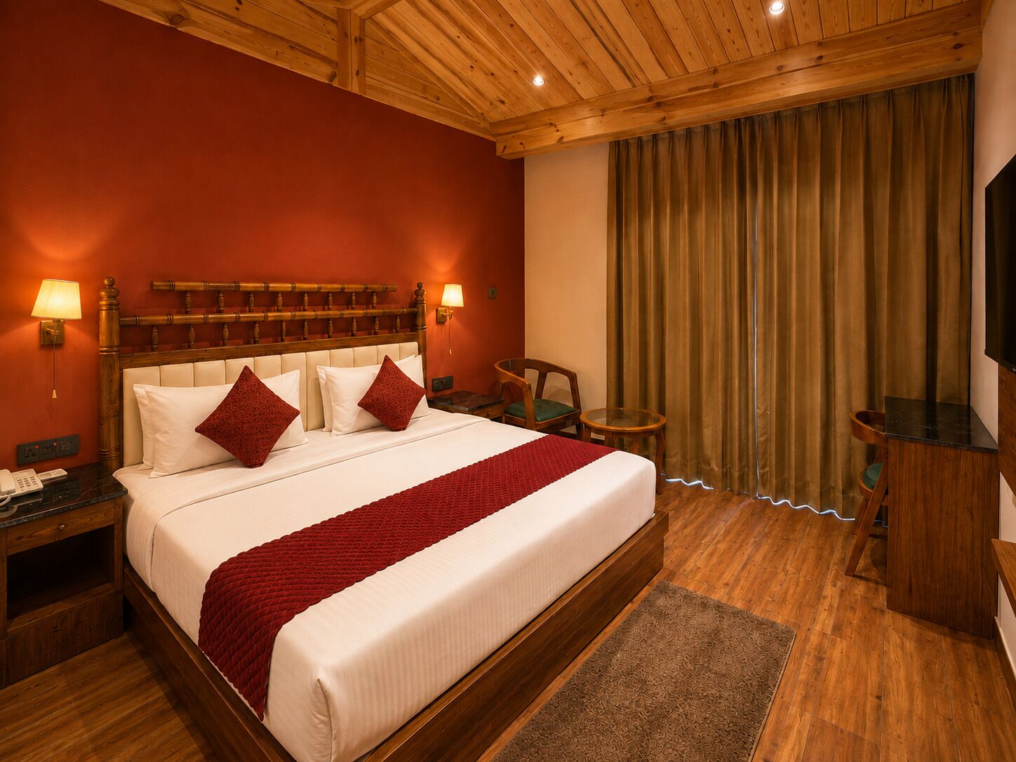 Een hotelkamer met een groot bed, een houten hoofdeinde, twee bedlampen, een bureau met stoel en een televisie.