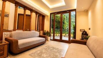 Una sala de estar moderna con un sofá, un tapete estampado y vistas al verdor exterior.