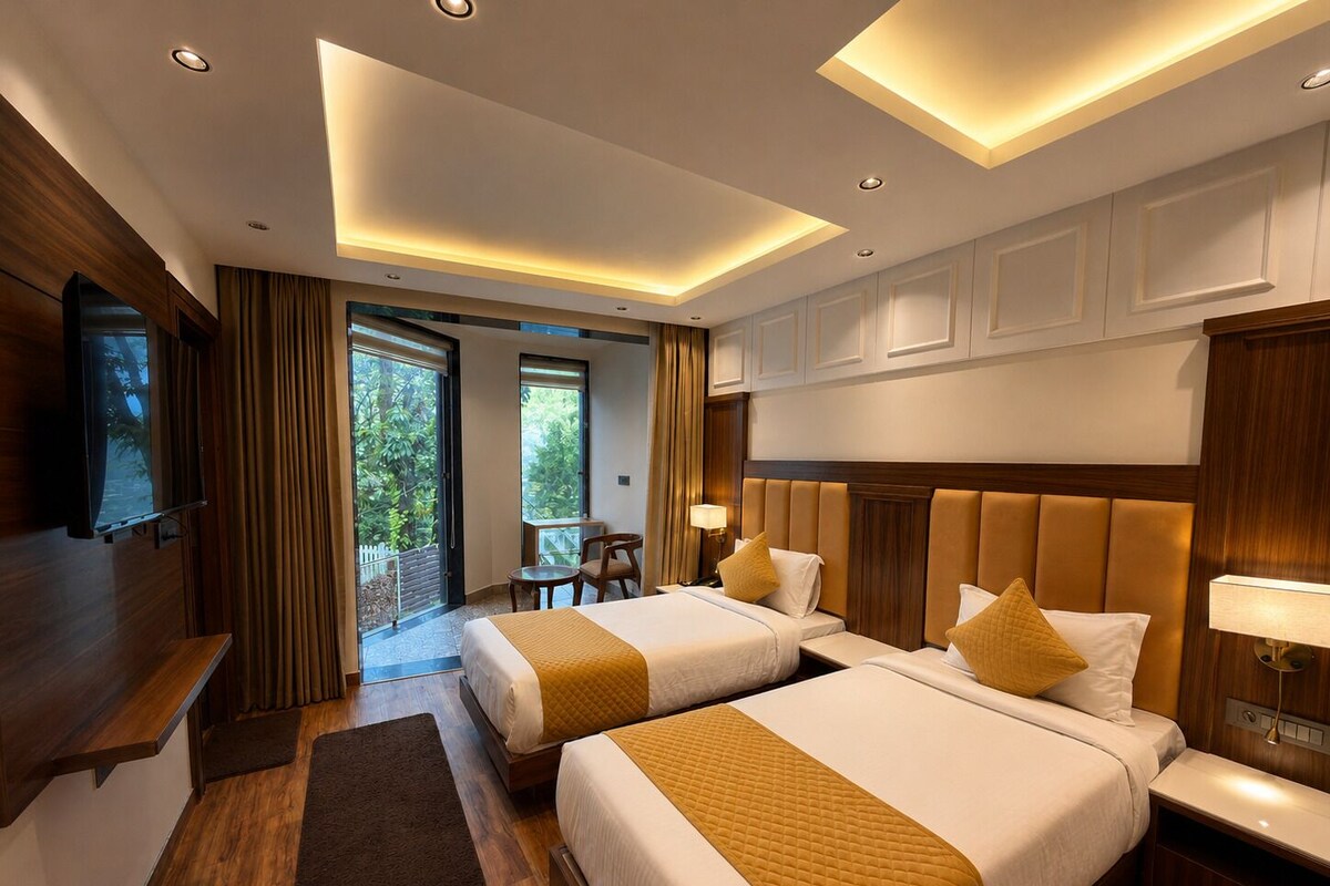 A hotel room with two beds, a TV, a desk, and a balcony with curtains.